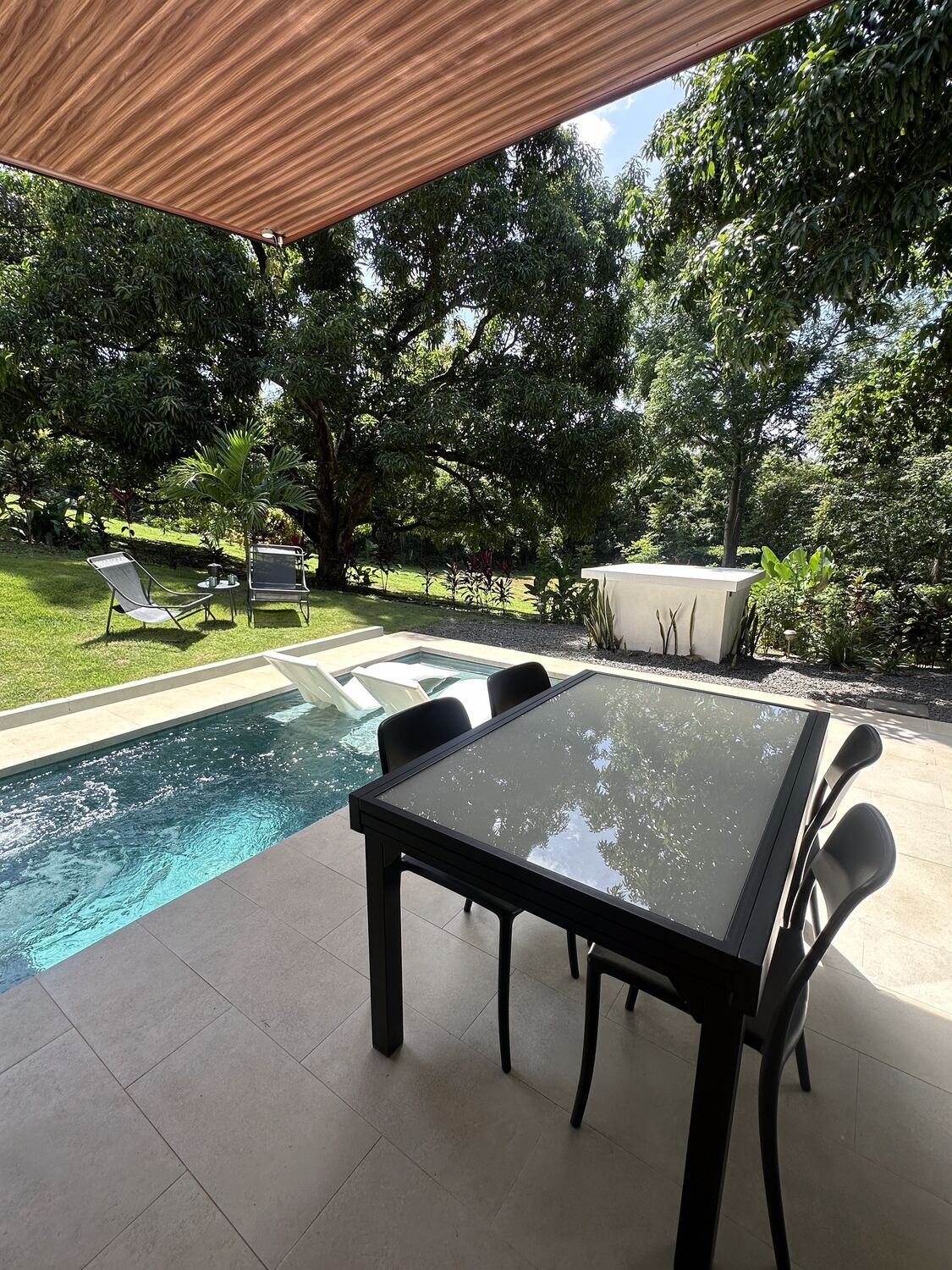 Dining table on the covered terrace, right beside the private pool, with the garden beyond